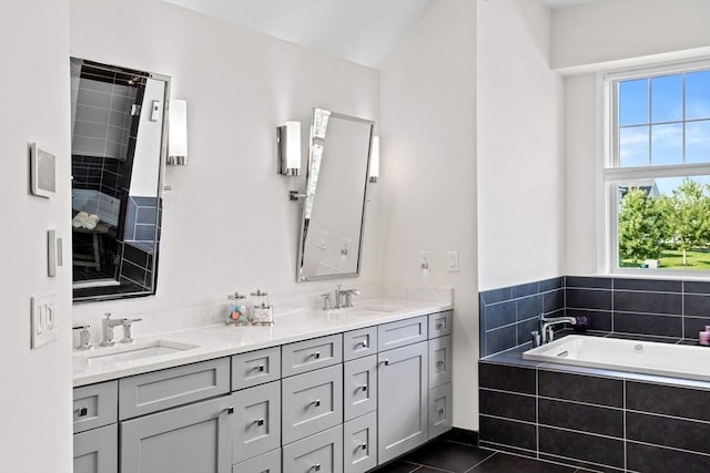 bathroom with double vanity, a garden tub, tile patterned flooring, and a sink