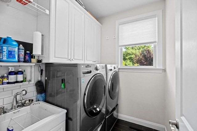 washroom with dark wood-style flooring, a sink, baseboards, independent washer and dryer, and cabinet space