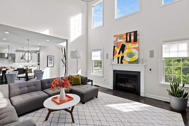 living area with a fireplace with flush hearth, baseboards, wood finished floors, and recessed lighting