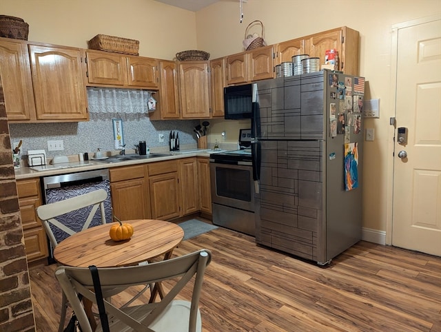 kitchen featuring sink, stainless steel appliances, backsplash, and hardwood / wood-style floors