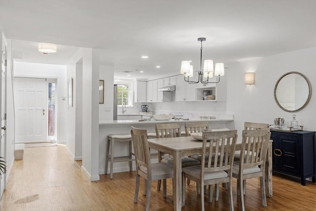 dining space featuring light wood-style floors, baseboards, recessed lighting, and a chandelier