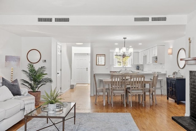 living room with an inviting chandelier, recessed lighting, light wood-style floors, and visible vents