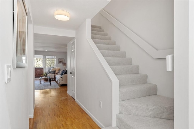 staircase with baseboards and wood finished floors
