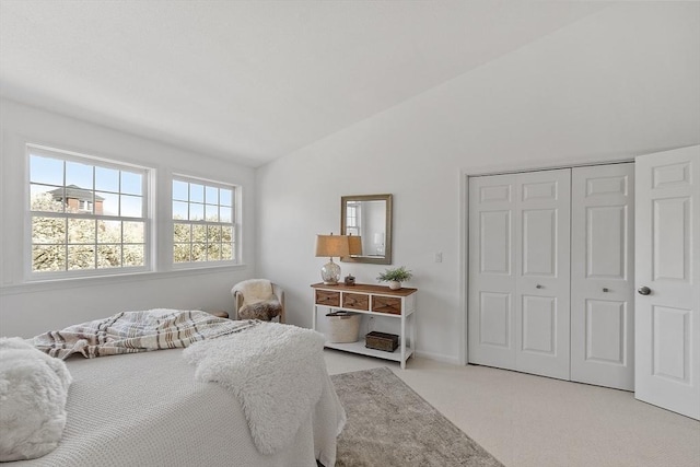 bedroom featuring a closet, vaulted ceiling, and light colored carpet