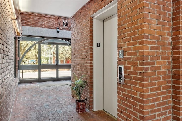 entrance to property featuring french doors, elevator, and brick siding