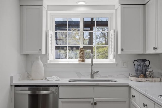 kitchen featuring stainless steel dishwasher, a sink, white cabinetry, and light countertops