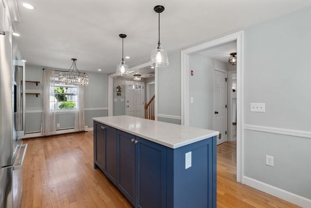 15 Janet Rd, Arlington, MA 02474 - kitchen with blue cabinets, light wood-style flooring, light countertops, a kitchen island, and decorative light fixtures