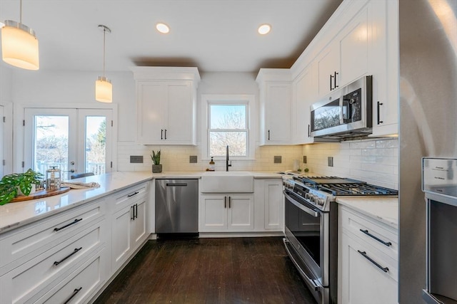 kitchen featuring decorative light fixtures, white cabinetry, stainless steel appliances, french doors, and sink