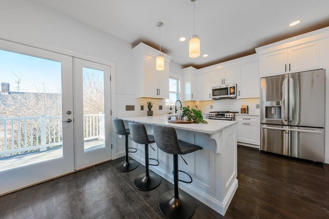 kitchen featuring white cabinets, dark hardwood / wood-style flooring, stainless steel appliances, hanging light fixtures, and a breakfast bar