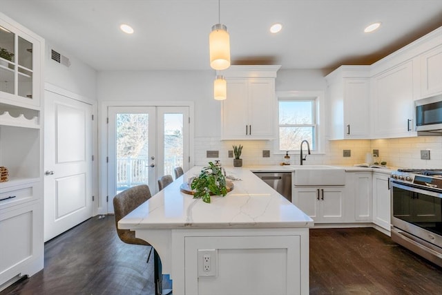 kitchen featuring white cabinetry, a kitchen breakfast bar, stainless steel appliances, and pendant lighting