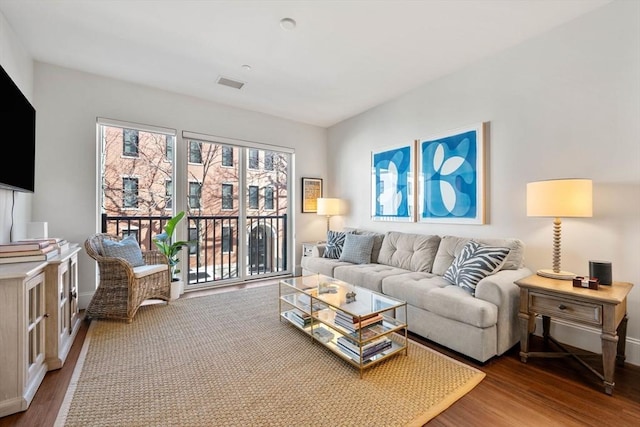 living room with visible vents, baseboards, and wood finished floors