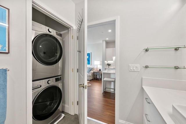 washroom featuring laundry area, wood finished floors, and stacked washer and clothes dryer