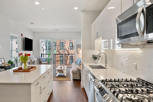 kitchen featuring dark wood-style flooring, appliances with stainless steel finishes, light countertops, and a sink