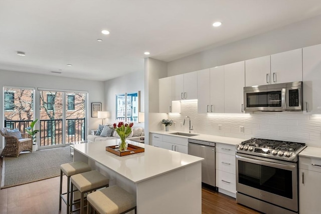 kitchen with a sink, open floor plan, stainless steel appliances, light countertops, and a healthy amount of sunlight