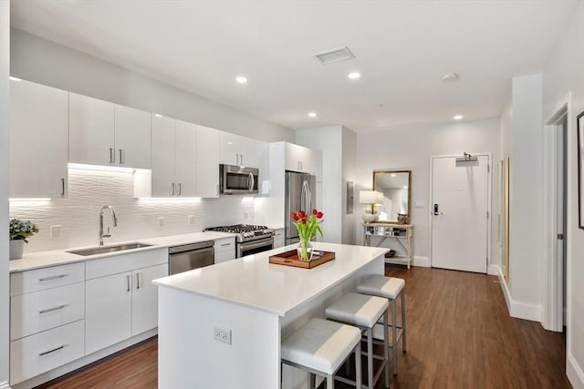 kitchen featuring visible vents, a center island, a breakfast bar area, appliances with stainless steel finishes, and a sink