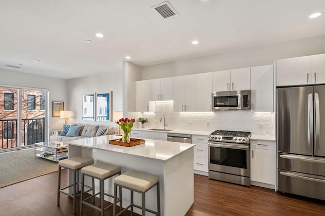 kitchen featuring visible vents, a sink, light countertops, appliances with stainless steel finishes, and a kitchen bar