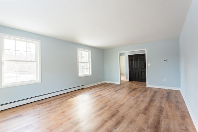 empty room with light hardwood / wood-style flooring and a baseboard heating unit