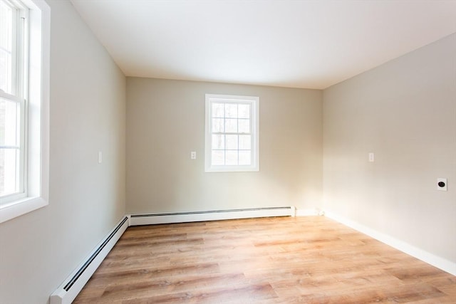 unfurnished room with a baseboard heating unit and light hardwood / wood-style floors