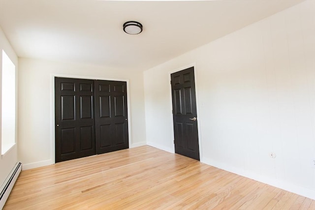 unfurnished bedroom featuring a closet, a baseboard radiator, and hardwood / wood-style flooring