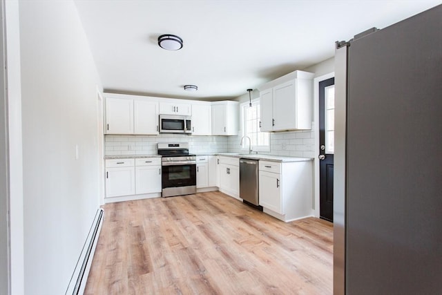 kitchen with appliances with stainless steel finishes, white cabinets, decorative light fixtures, and tasteful backsplash