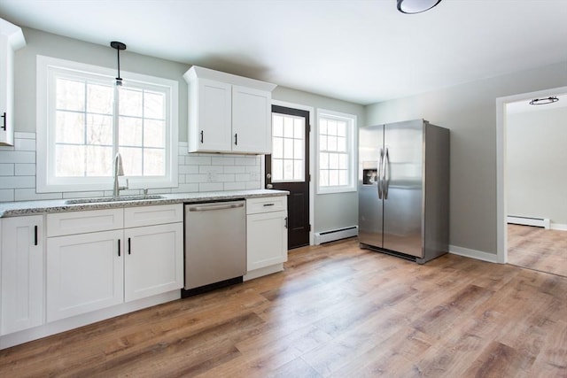 kitchen featuring stainless steel appliances, decorative backsplash, white cabinetry, and baseboard heating