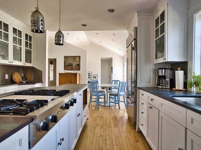 kitchen featuring glass insert cabinets, dark countertops, pendant lighting, and white cabinets