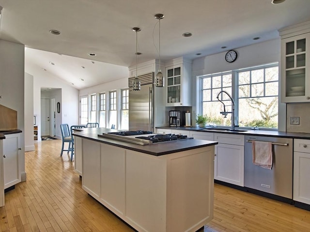 kitchen featuring hanging light fixtures, appliances with stainless steel finishes, dark countertops, and glass insert cabinets