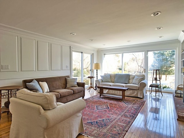 living area with ornamental molding, a decorative wall, and hardwood / wood-style flooring