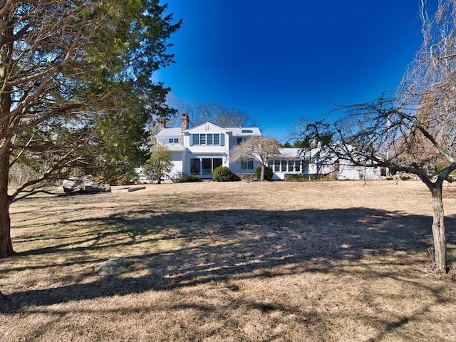 back of house with a yard, a chimney, and a sunroom