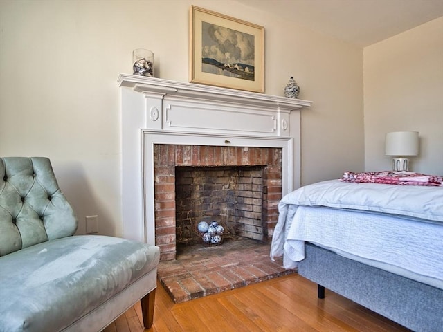 bedroom with a fireplace and wood finished floors