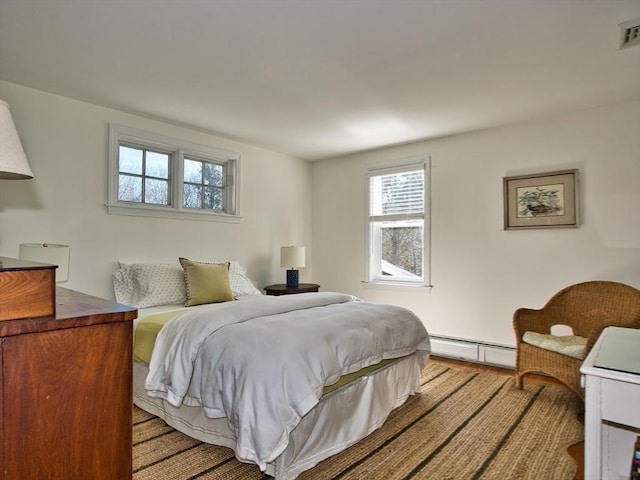 bedroom with a baseboard heating unit and light wood finished floors