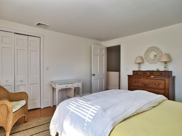 bedroom featuring a closet, visible vents, and wood finished floors