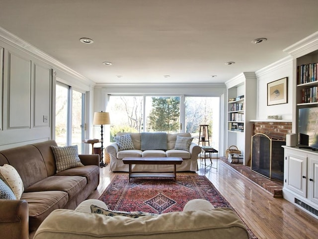 living area with built in shelves, a healthy amount of sunlight, and crown molding