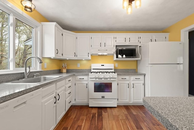 kitchen featuring white cabinets, a sink, white appliances, under cabinet range hood, and dark wood-style floors