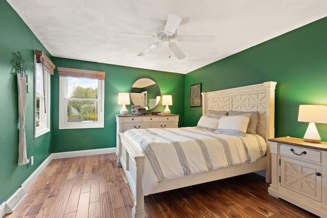 bedroom with baseboards, ceiling fan, wood finished floors, and visible vents