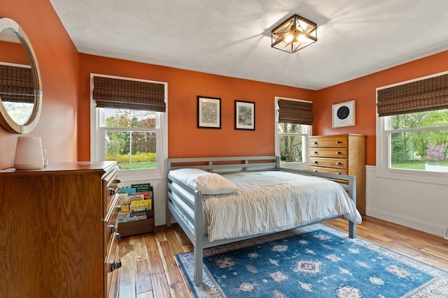 bedroom featuring baseboards, multiple windows, and wood finished floors