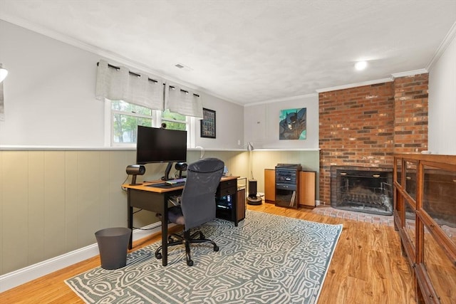 office area with a brick fireplace, ornamental molding, wood finished floors, and a wainscoted wall
