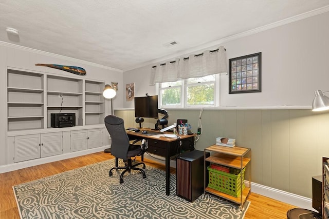 home office featuring wainscoting, visible vents, ornamental molding, and light wood finished floors