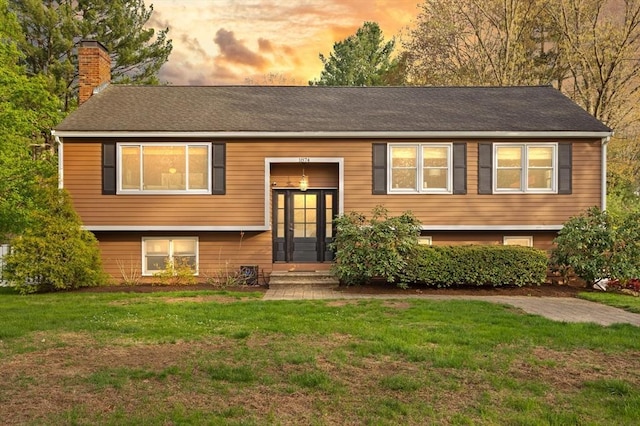 bi-level home featuring a yard and a chimney
