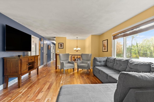 living area featuring an inviting chandelier, light wood finished floors, and baseboards