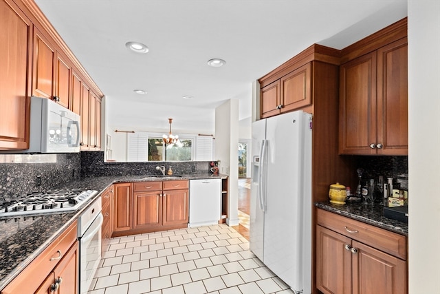 kitchen with light tile patterned flooring, backsplash, decorative light fixtures, an inviting chandelier, and white appliances