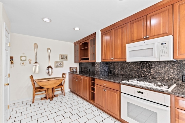 kitchen with dark stone countertops, backsplash, white appliances, and pendant lighting