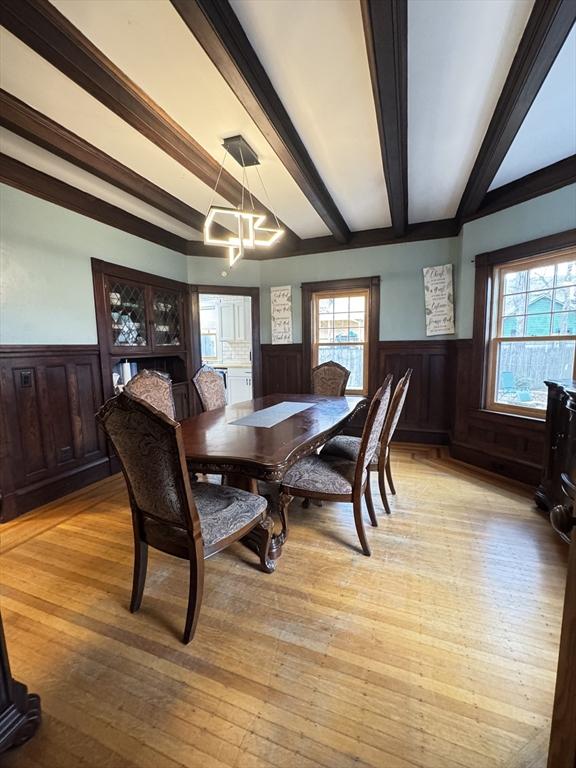 dining room with beamed ceiling, light hardwood / wood-style flooring, and a chandelier