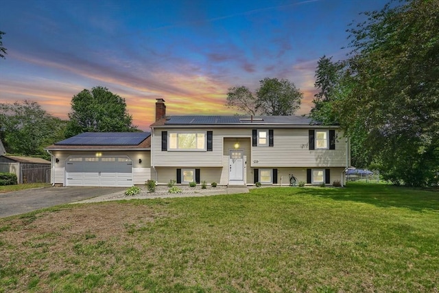 216 Pineview Cir, Agawam, MA 01001 - bi-level home featuring an attached garage, a chimney, roof mounted solar panels, and asphalt driveway