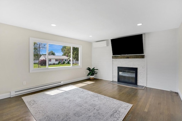 216 Pineview Cir, Agawam, MA 01001 - unfurnished living room with a baseboard heating unit, a stone fireplace, wood finished floors, a wall mounted air conditioner, and baseboards