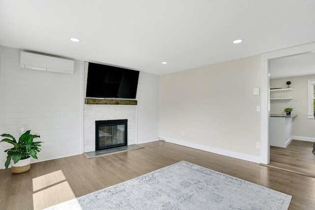 216 Pineview Cir, Agawam, MA 01001 - unfurnished living room with a wall mounted air conditioner, a glass covered fireplace, wood finished floors, baseboards, and recessed lighting