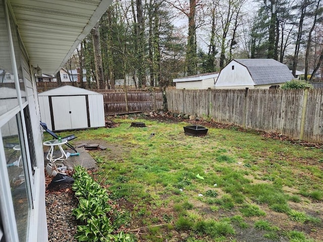 view of yard with a fenced backyard, a storage shed, and an outbuilding
