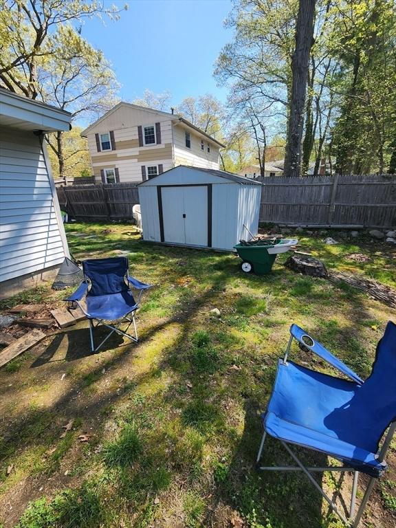view of yard with a fenced backyard, an outdoor structure, and a storage shed