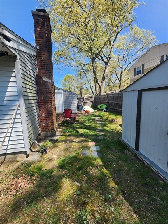 view of yard featuring an outbuilding, fence, and a storage unit
