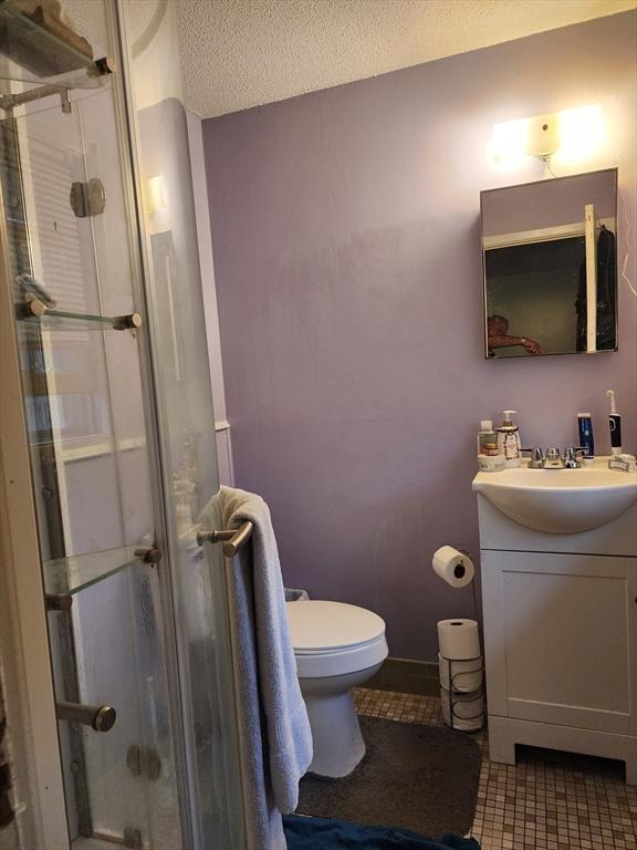 bathroom featuring toilet, a stall shower, tile patterned floors, a textured ceiling, and vanity